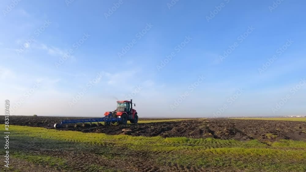 Red modern tractor, a self-driving wheeled machine that performs agricultural work in the field. A tractor with a reverse plow plows the field. Agribusiness. Red modern tractor, a self-driving wheeled machine that performs agricultural work in the field. A tractor with a reverse plow plows the field. Agribusiness.