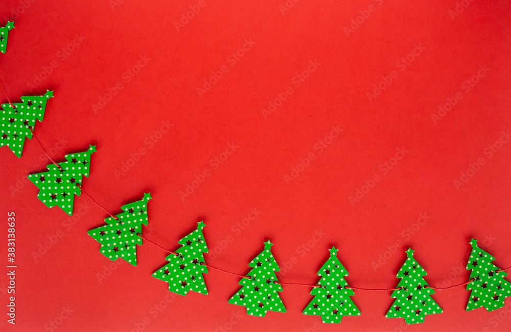Christmas and Happy New Year flat lay. Composition of garland of green Christmas trees on red background. Flatlay, top view, copy space