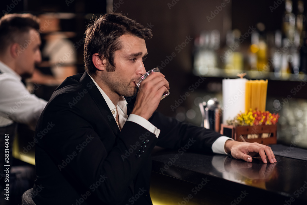a young man drinks water with lemon at the bar in a nightclub.