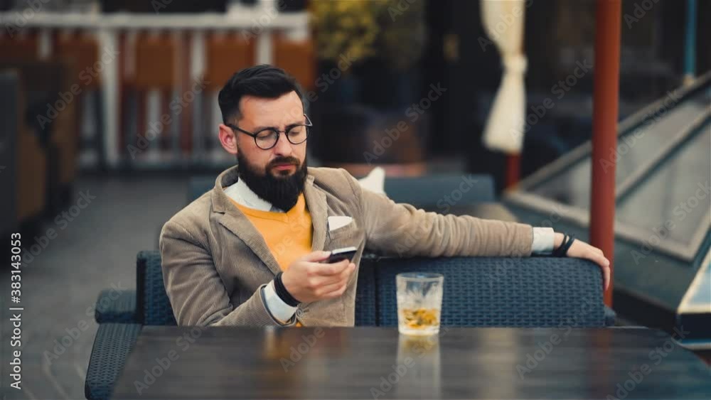 Modern hipster businessman in glasses using mobile phone and drinking Modern hipster businessman in glasses using mobile phone and drinking