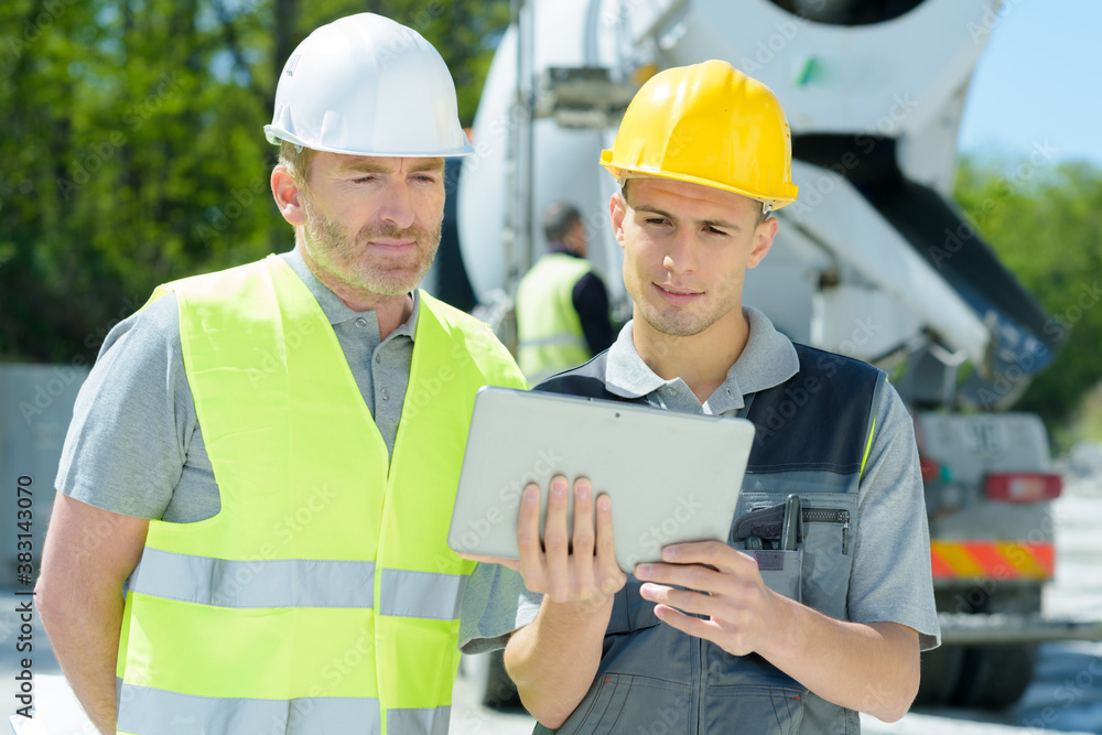 two workers on a construction site using a tablet two workers on a construction site using a tablet