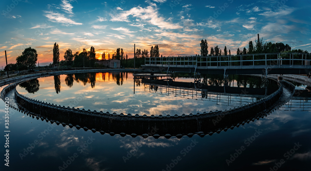 Naklejka premium Modern sewage treatment plant. Round wastewater purification tanks at sunset.