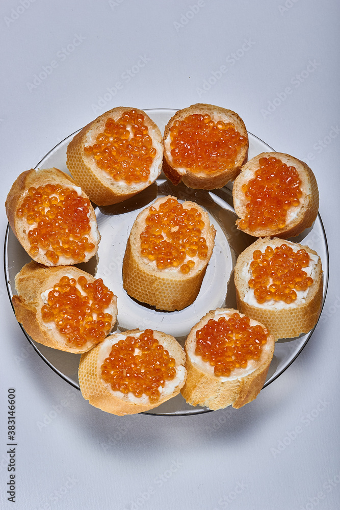Sandwiches with butter and delicious red caviar on a plate on a white background Sandwiches with butter and delicious red caviar on a plate on a white background