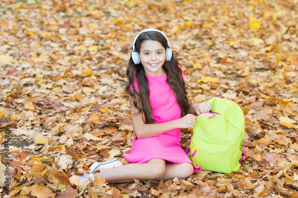 school girl wear headphones while sit near backpack outdoor, back to school school girl wear headphones while sit near backpack outdoor, back to school