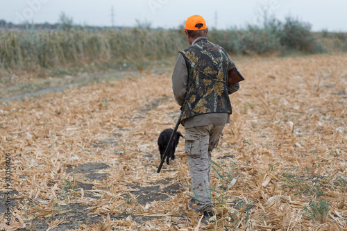 Duck hunter with shotgun walking through a meadow. .Rear view of a man with a weapon in his hands. © Mountains Hunter