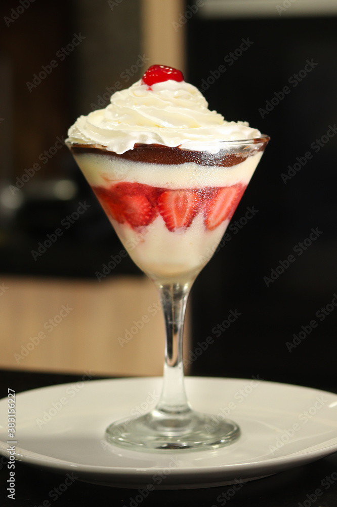 A bowl with a strawberry dessert with cherry, whipped cream and chocolate A bowl with a strawberry dessert with cherry, whipped cream and chocolate