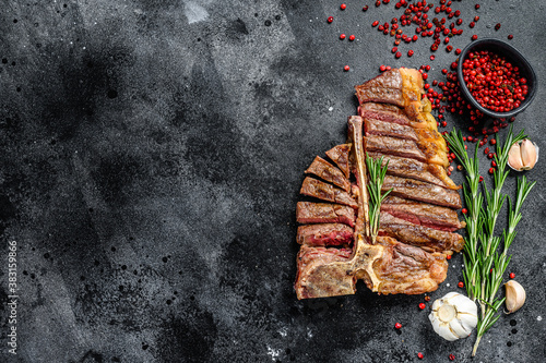 Sliced Grilled T-bone steak. Cooked tbone beef meat. Black background. Top view. Copy space photo