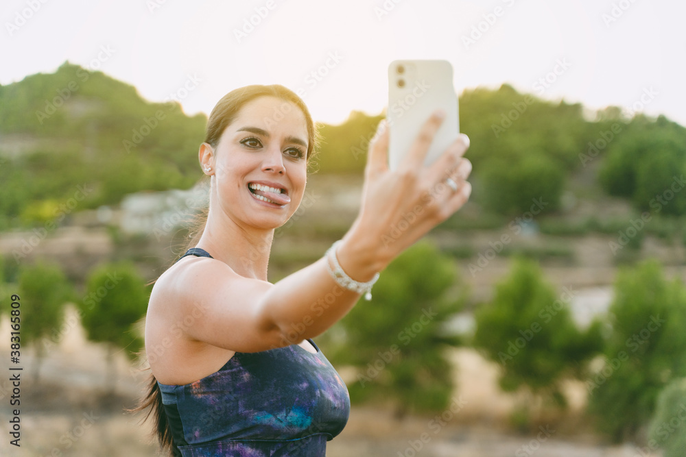 Young woman standing with a photo making a funny face, before starting to run. Healthy living, running in the mountains. Young woman standing with a photo making a funny face, before starting to run. Healthy living, running in the mountains.