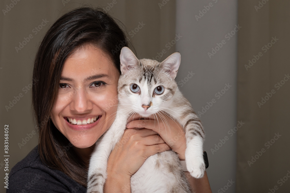 Happy woman and her white cat with stripes looking at the camera posing for a picture