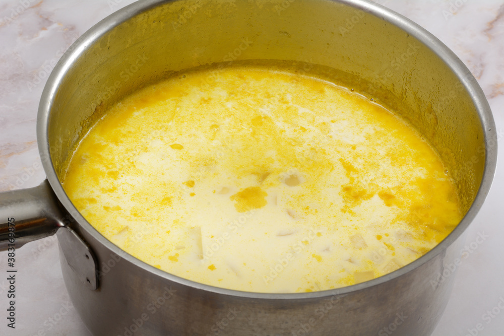 Making chowder soup with milk and chopped potatoes and mirepoix base in stainless steel cooking pot Making chowder soup with milk and chopped potatoes and mirepoix base in stainless steel cooking pot