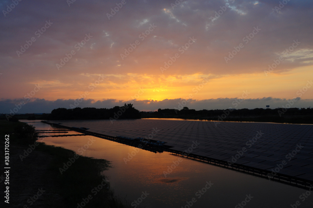 Sunset rays over solar panels on the lake.