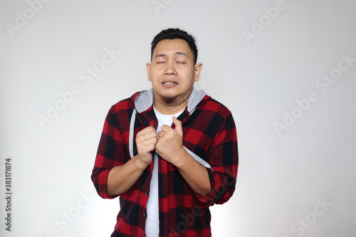 Young Asian man gets cold and fever, feeling deezy and shiver, against grey photo