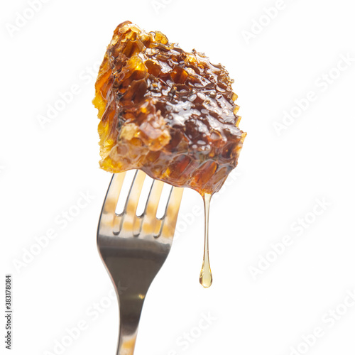 Drops of fresh honey drip from wax honey on a table fork. vitamin nutrition and bee product.
