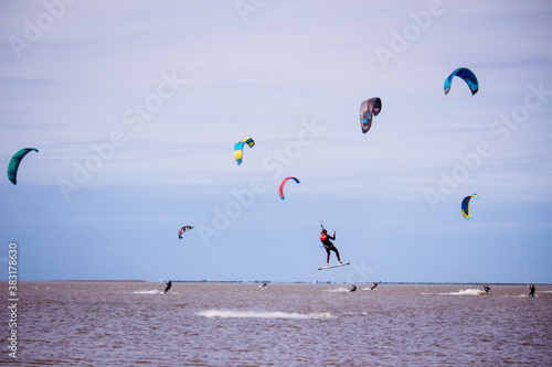 several kitesurfing sails in a lagoon on a cloudy day - man in the air