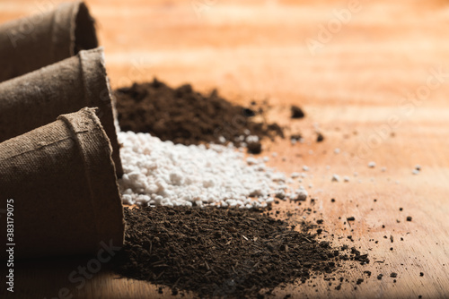 Billede på lærred Worm humus, perlite and peat moss coming out of peat pots as substrate materials for soil mix on a wooden raw surface with space for text