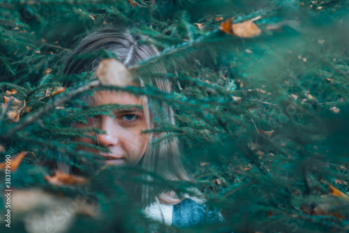 a girl wanders through the woods, peeps out from under the Christmas tree, in search of a way. The girl's gaze through the foliage in the woods.