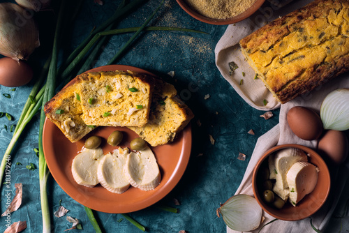 Traditional paraguayan food known as sopa paraguaya on a brown ceramic plate, with cornmeal, eggs, onions, onion leaves and paraguayan cheese as ingredients, green olives in the plate as a decoration. photo