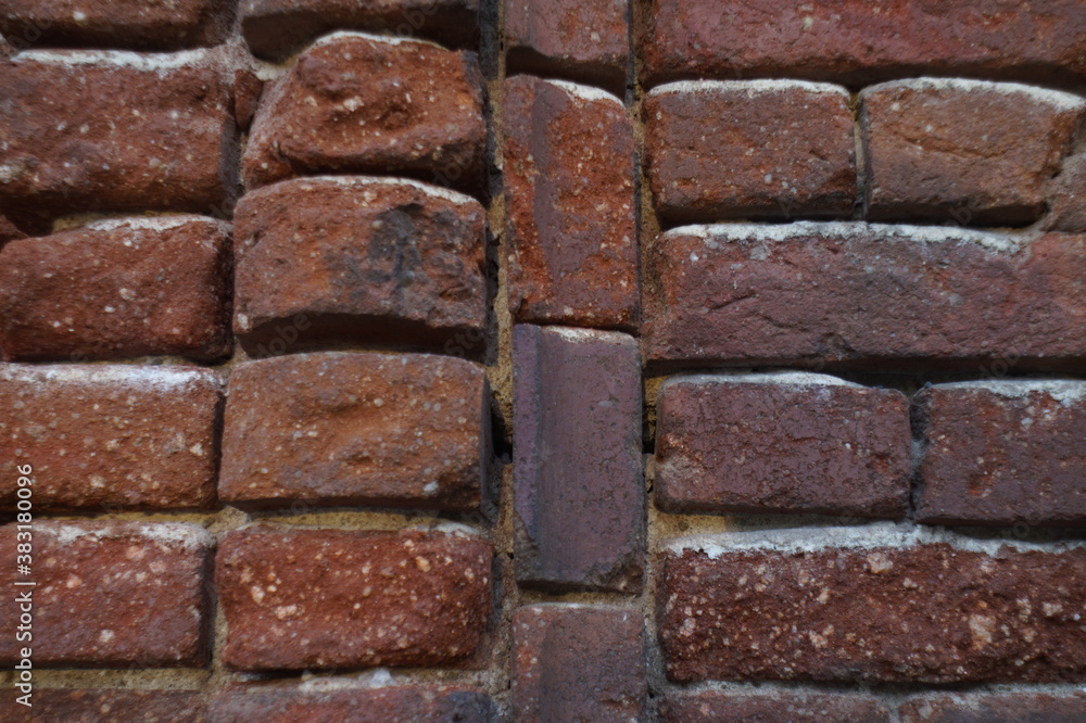 Photo of the exterior surface of an ancient brick wall. Abundant traces of time on the red brick and in the destroyed layer of mortar. In dark red tones. Photo of the exterior surface of an ancient brick wall. Abundant traces of time on the red brick and in the destroyed layer of mortar. In dark red tones.