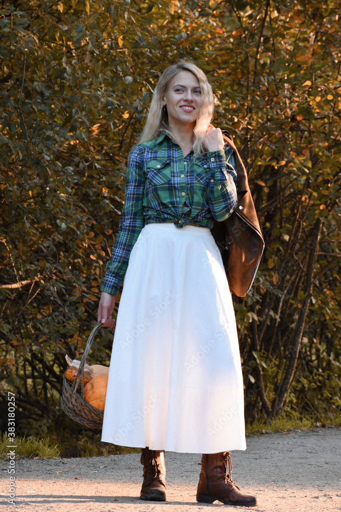 A girl dressed in a country style stands on an autumn forest path with a basket of pumpkins in her hands.
A girl dressed in a country style stands on an autumn forest path with a basket of pumpkins in her hands.