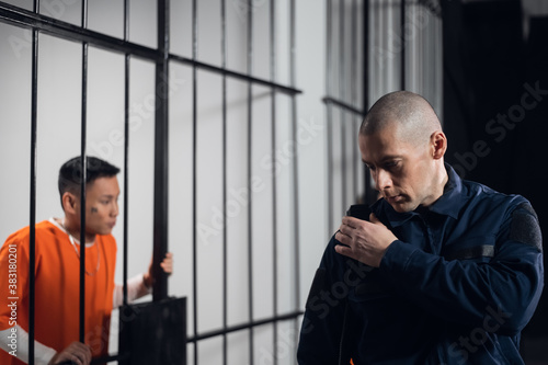 A stern, bald prison warden makes the rounds of the cells and transmits information over the radio to the head of the prison guard