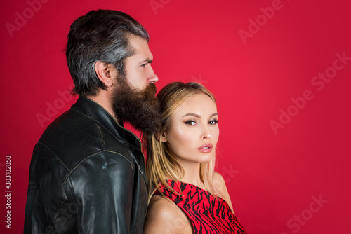 Sensual young woman and her bearded lover. Fashion couple on red.