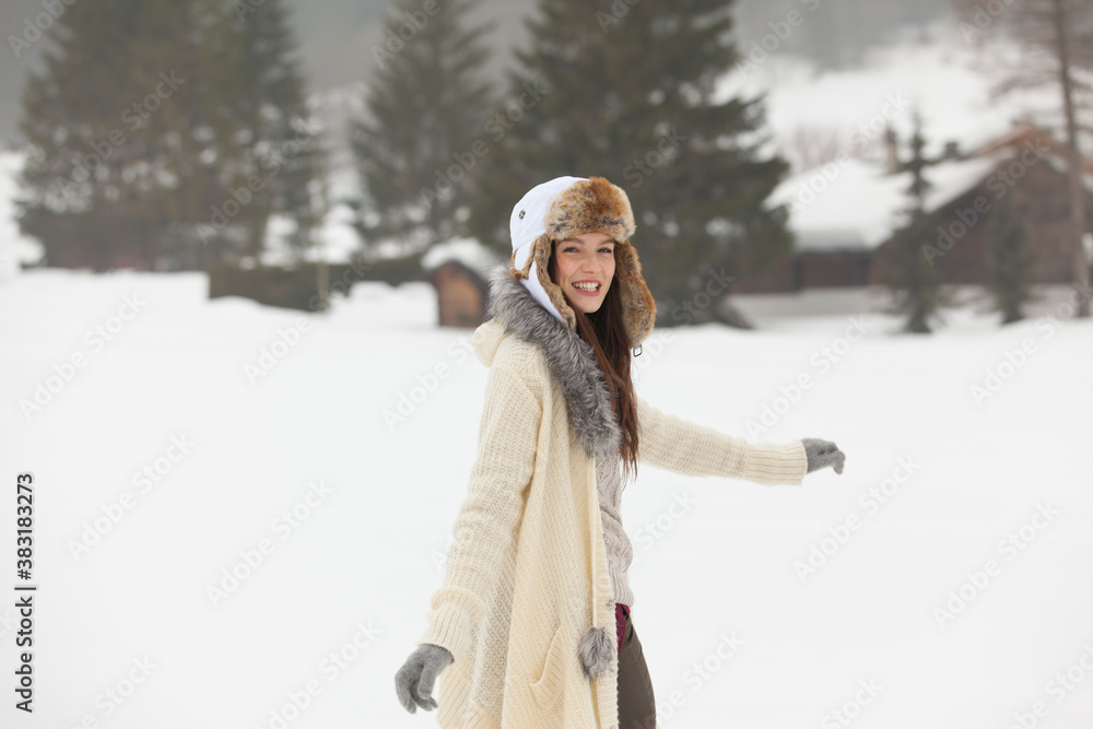 Fototapeta premium Portrait happy young woman in fur hat walking in snow