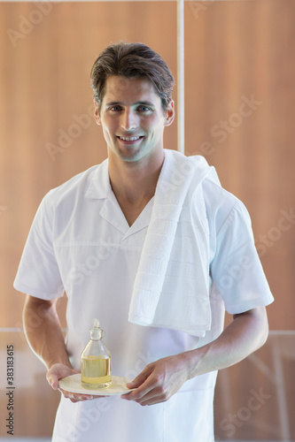 Fotografija Portrait confident young male masseuse holding massage oil