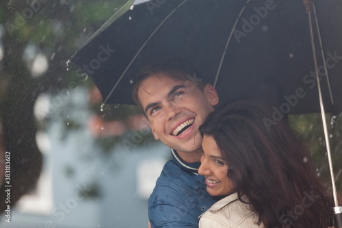 Happy young couple with umbrella in rain