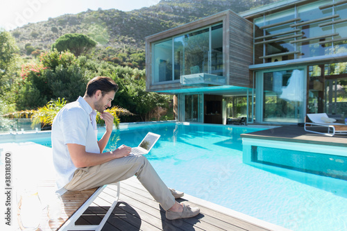 Canvastavla Young man using laptop at sunny luxury poolside