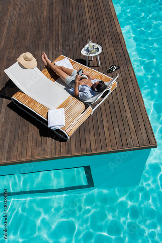 Young man relaxing on lounge chair at sunny summer poolside