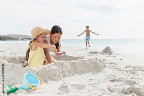 Mother and daughter building sandcastle on beach