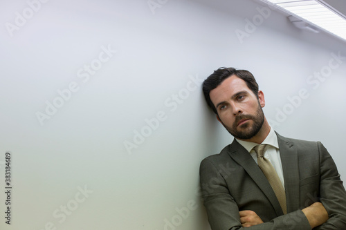 Bild auf Leinwand Exhausted corporate businessman leaning against wall