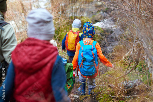 group of children with backpacks walking along mountain path