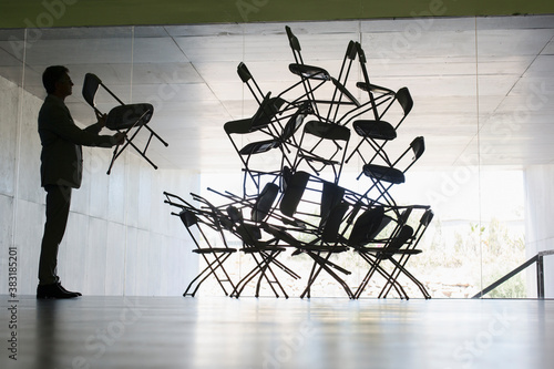 Fotografie Businessman stacking chairs in office