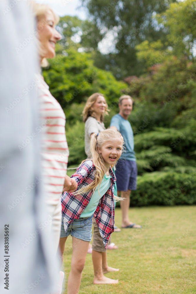 Fototapeta premium Portrait happy girl with multi-generation family in backyard