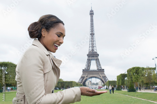 Photography Playful woman pretending to hold Eiffel Tower in palm, Paris, France