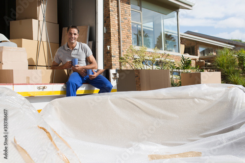 Bilde på lerret Portrait confidant male mover with coffee at back of moving van
