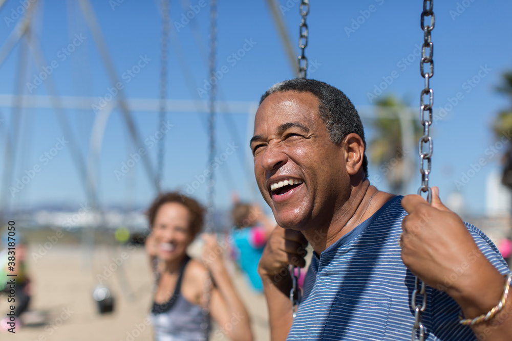 Obraz premium Happy senior man on swing set on sunny beach