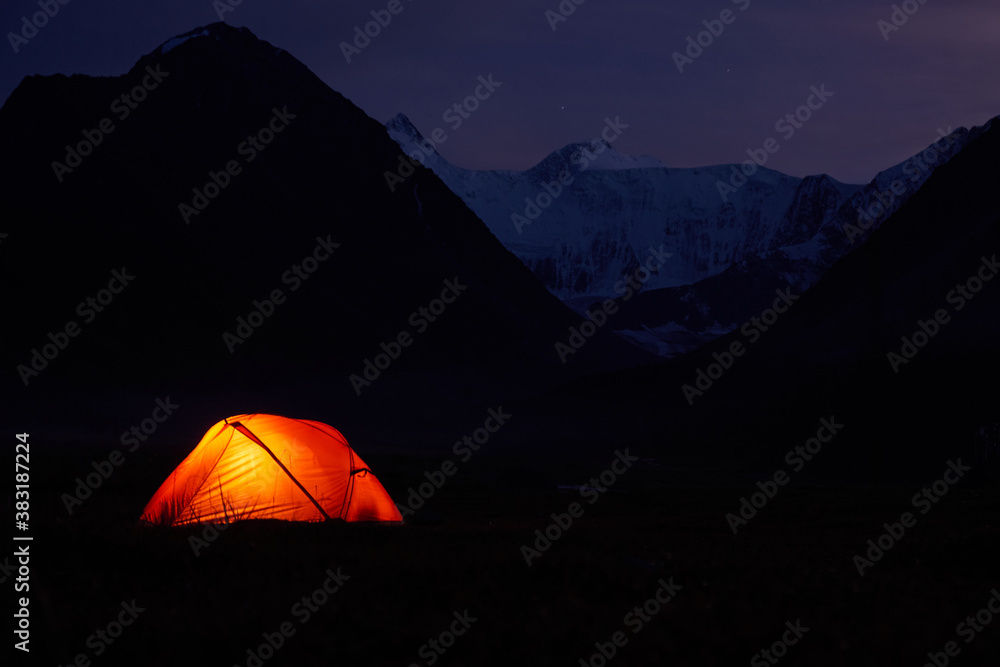 Tent Glowing red under in Belukha Mountain, Altai, a night sky full of stars.