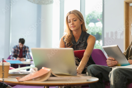 Young female college student studying at laptop in student lounge Free Download Young female college student studying at laptop in student lounge - GFXLoad