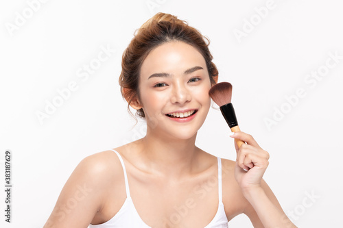 Beautiful Asian young woman smile and holding make up brush with healthy Clean and Fresh skin feeling so happiness and cheerful,Isolated on white background,Beauty Cosmetics Concept