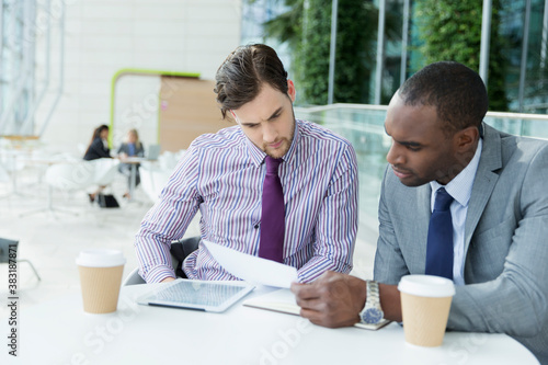 Businessmen reviewing paperwork at cafe