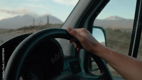 Hand gripping the steering wheel driving through the country