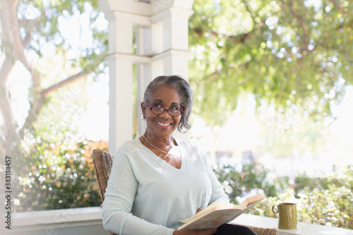 Картината върху платно Portrait happy senior woman reading book on sunny porch