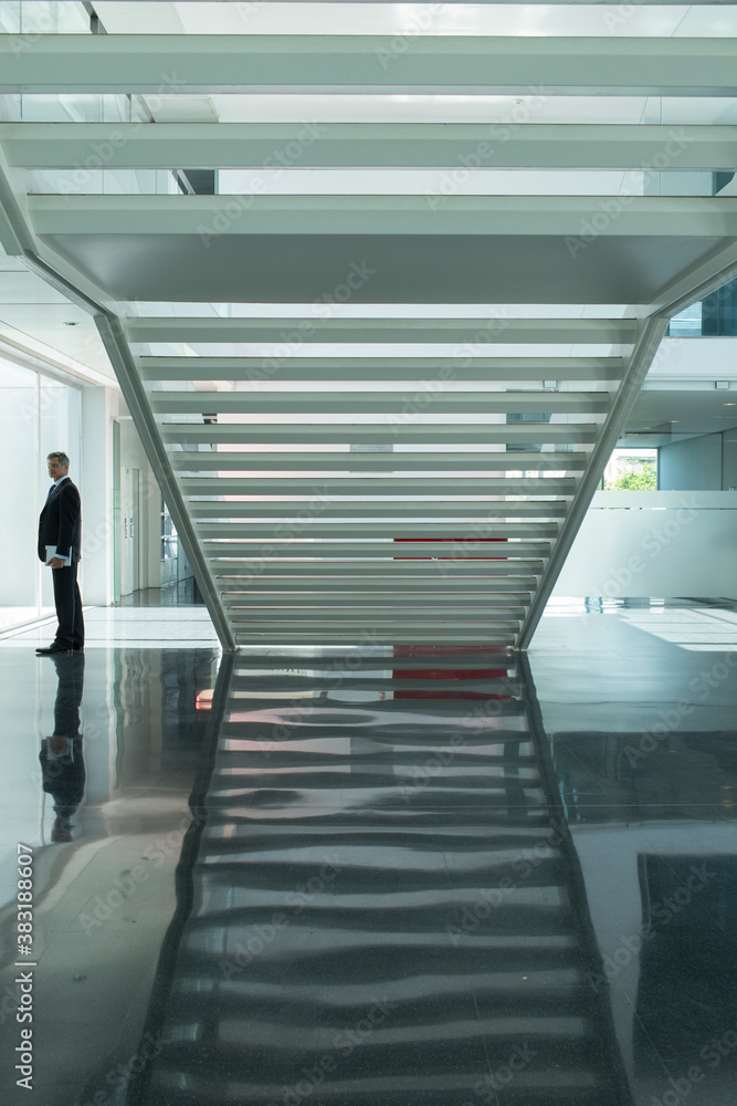 Obraz premium Businessman in modern lobby with staircase