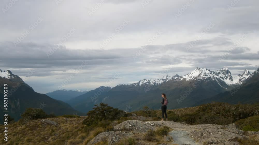 Woman looking at epic mountain view then walking down hill Woman looking at epic mountain view then walking down hill