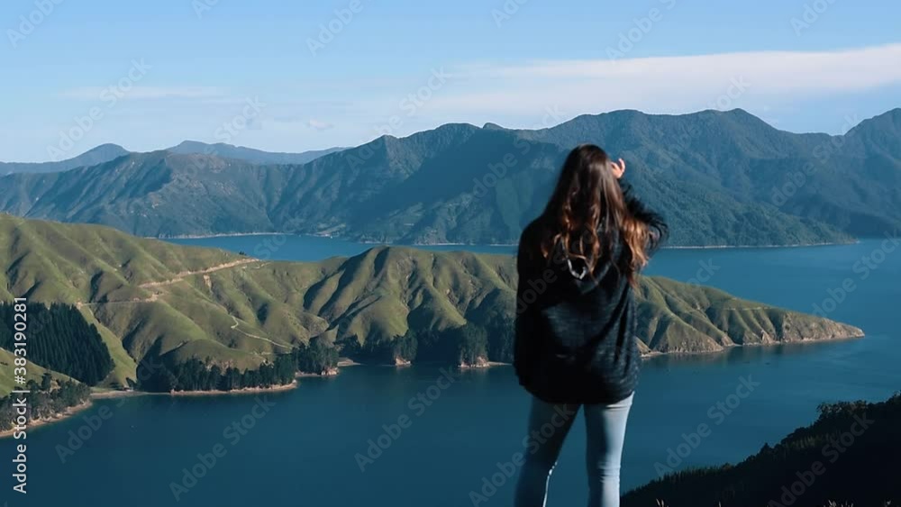 Woman looking at ocean bay and green rolling hills Woman looking at ocean bay and green rolling hills