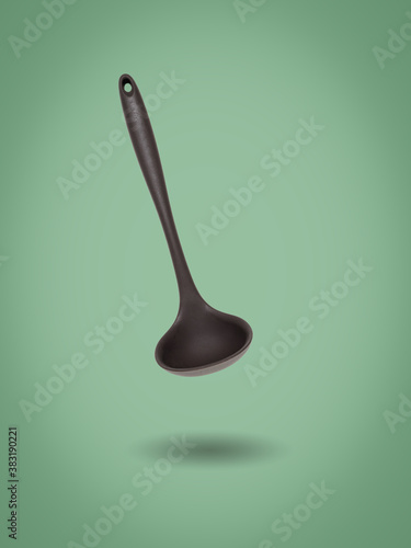 Kitchen silicone ladle on a green background.
