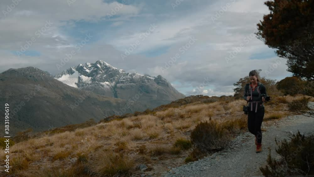 Female photographer on location in the mountains hiking downhill Female photographer on location in the mountains hiking downhill