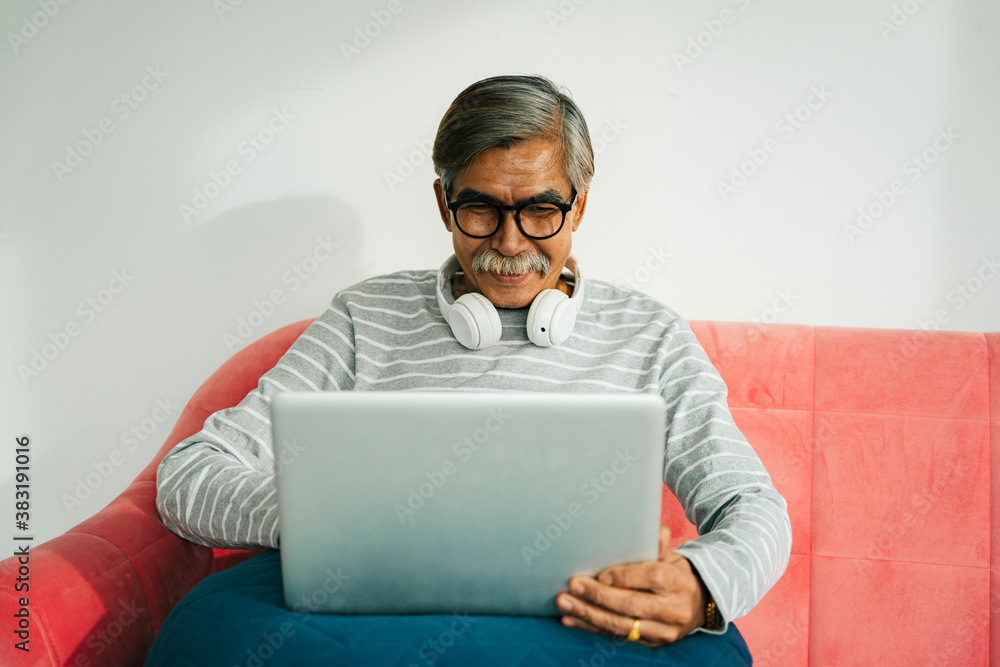 Old elderly senior man wear eyeglasses sit on a couch using laptop. Old elderly senior man wear eyeglasses sit on a couch using laptop.